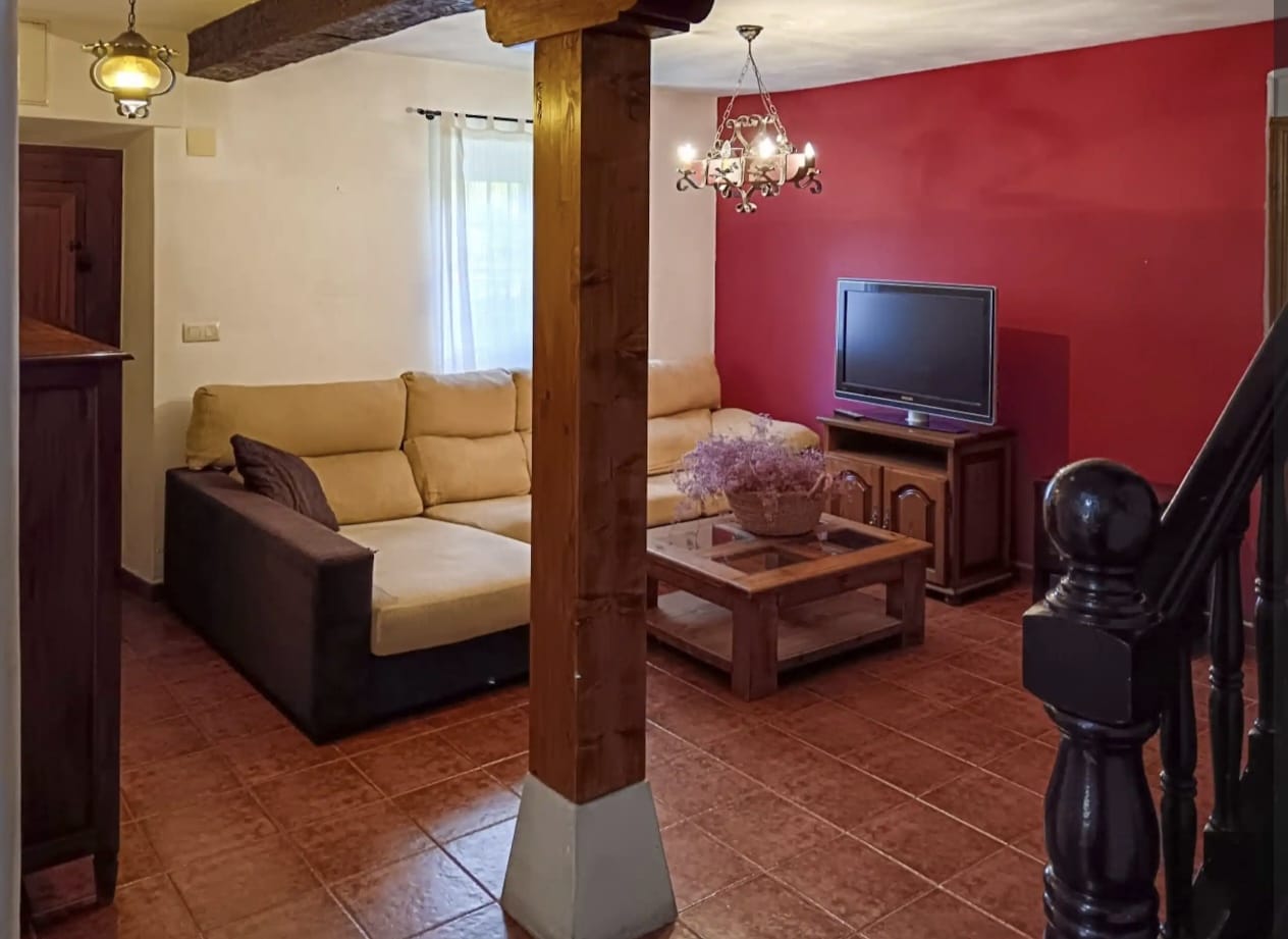Salón rústico con vigas de madera en casa rural gestionada por Stailya